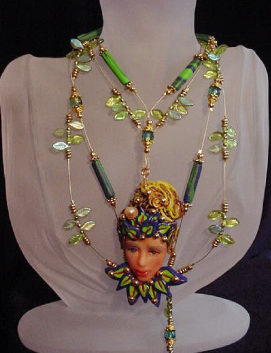 Handcrafted Fairy Face Green Necklace-Handmade with Polymer Clay. Findings, crimps and clasp are 14K gold plated. Gold plated Beadalon .018 in wire is also used. Glass and brass beads are used for final details. Water pearl for final detail. Unique design!