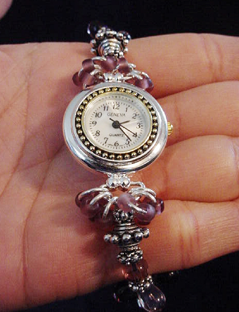 Handcrafted Jewelry Pink & Purple Watch-Handcrafted with Drop Glass Purple & Pink beads. Embellished with Silver plated  findings and details. Stretch cord is used for watch band. Round silver and gold details watch face.White Opalescent Geneva sphere. Quartz function and mechanical system. Stainless Steel back and is water resistant.Beautiful and Elegant!