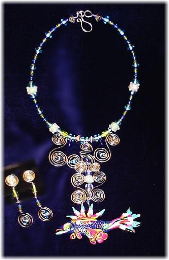 Fimo Fish Pendant Necklace and Earrings Set;This beautiful set is made with beautiful watery colors glass beads. Necklace fish pendant is made of glazed Fimo.  Pewter findings are added for final details. Nickel wire is used for the clasps. Silver plated wire is used to embellish the glass beads and the Fimo creation. Very Unique and elegant!