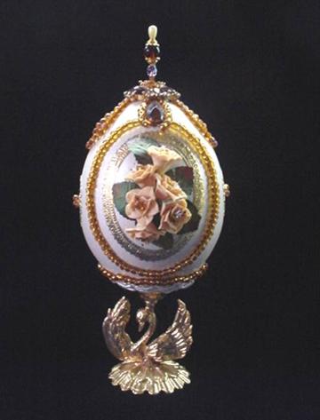 This flowery carved eggypiece is painted in pearly light yellow, pearly light pink and gold enamel details. Inside, a bunch of handmade peach, yellow, light pink and purple porcelain roses create the garden ambiance. Clay stand w/gold enamel and glitter finish. AB Austrian Crystals, crystals and glass beads are used for final details. Decorated box available for this eggypiece. 