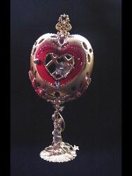 Heart Jewel Eggypiece- Front red heart door opens. Inside, one large drop AB Austrian Crystal and red heart shaped crystal, both resting on a red velvet pillow with gold color details. This piece was imperial gold color and red satin finish. Accented with AB Austrian Crystals and red Ruby crystals. 18K gold plated stand and findings. Decorated box available for this eggypiece. 