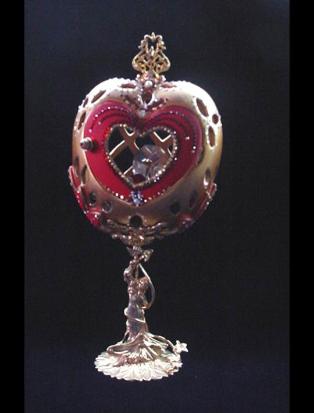  Front red heart door opens. Inside, one large drop AB Austrian Crystal and red heart shaped crystal, both resting on a red velvet pillow with gold color details. This piece was imperial gold color and red satin finish. Accented with AB Austrian Crystals and red Ruby crystals. 18K gold plated stand and fidings. Decorated box available for this eggypiece.