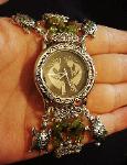 Handcrafted Semi-precious Kokopelli Watch 1 -  Handcrafted with Semi-precious Unachite and Peridot Stones. Embellished with Silver plated  beads and findings. Five turtle charms are used for final details. Stretch cord is used for watch bands. Round Large Silver watch face. Two Kokopelli's designs enhance the watch sphere. Quartz function and mechanical system. Stainless Steel back. Beautiful, Elegant and Southern look.