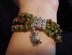 Handcrafted Semi-precious Kokopelli Watch 1-  Handcrafted with Semi-precious Unachite and Peridot Stones. Embellished with Silver plated  beads and findings. Five turtle charms are used for final details. Stretch cord is used for watch bands. Round Large Silver watch face. Two Kokopelli's designs enhance the watch sphere. Quartz function and mechanical system. Stainless Steel back. Beautiful, Elegant and Southern look.