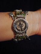 Handcrafted Semi-precious Kokopelli Watch 1 -  Handcrafted with Semi-precious Unachite and Peridot Stones. Embellished with Silver plated  beads and findings. Five turtle charms are used for final details. Stretch cord is used for watch bands. Round Large Silver watch face. Two Kokopelli's designs enhance the watch sphere. Quartz function and mechanical system. Stainless Steel back. Beautiful, Elegant and Southern look.