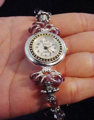 Handcrafted Jewelry Pink & Purple Watch - Handcrafted with Drop Glass Purple & Pink beads. Embellished with Silver plated  findings and details. Stretch cord is used for watch band. Round silver and gold details watch face. White Opalescent Geneva sphere. Quartz function and mechanical system. Stainless Steel back and is water resistant. Beautiful and Elegant! 