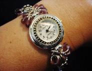 Handcrafted Jewelry Pink & Purple Watch - Handcrafted with Drop Glass Purple & Pink beads. Embellished with Silver plated  findings and details. Stretch cord is used for watch band. Round silver and gold details watch face. White Opalescent Geneva sphere. Quartz function and mechanical system. Stainless Steel back and is water resistant. Beautiful and Elegant! 