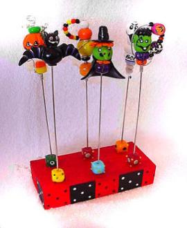 Polymer Halloween Food Picks - These unique handmade food picks will be the focal point in your party!BOO!! Handmade with polymer clay and decorated with glass beads, austrian crystals and wire. Each pick is aprox.6 in height , brass finished and washable. The set comes in a wooden handpainted base. Each set/6 comes in a clear PVC box for presentation. More seasonal designs will be available soon!