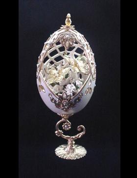 Painted in pearl ivory and gold enamel details. Accented with medium size AB Austrian Crystals. Top is movable. Completely and extremely delicate carved design. Inside, white porcelain roses embellish two gold plated butterflies. 18K gold plated stand and findings. Very Elegant! Perfect for wedding gift. Decorated box available for this eggypiece.