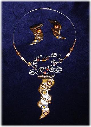 This clay handmade necklace is hand-painted in antique bronze, silver and gold. Accented w/glass beads, metal and clay handmade beads. Gold plated wire and posts are  used for final details. Unique Design and Very wild!